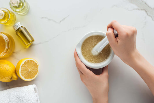 DIY: Hawaiian Black Lava Sea Salt Scrub being prepared in a bowl with essential oils and lemon slices.
